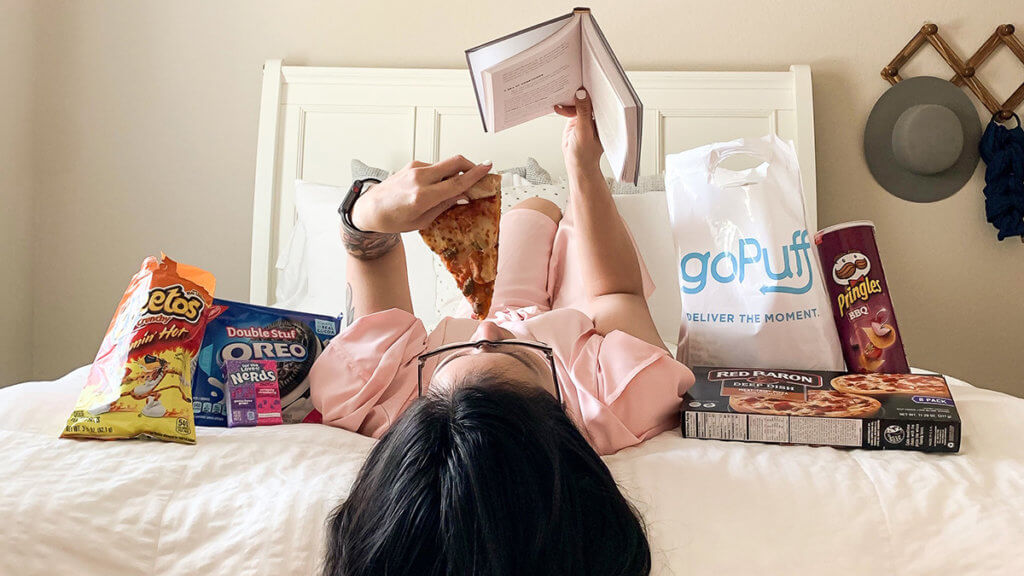 Girl reading on her bed while snacking