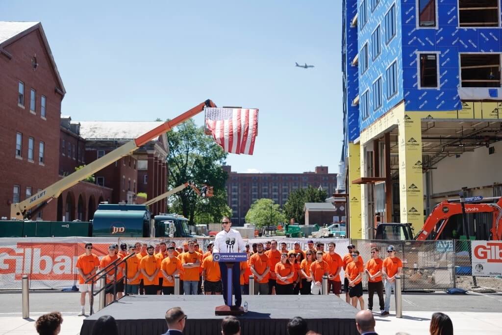 Pennsylvania Governor Josh Shapiro speaking from an outdoor podium during PA Sites Program Initiatives with employees on background