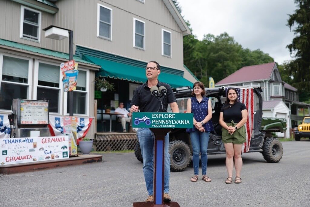 Governor Josh Shapiro at a podium announcing that the Department of Community and Economic Development (DCED) is awarding a $162,461 grant to the White Pine Country Store, Café & Lodge through the Marketing to Attract Tourists program.