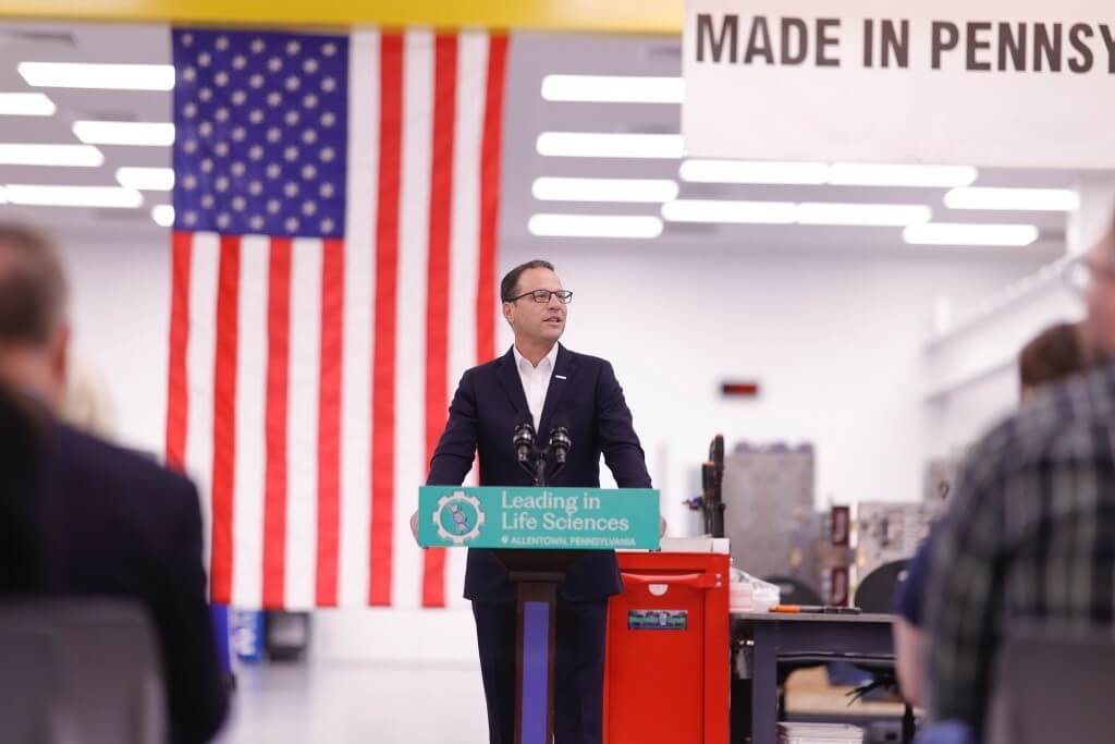 Pennsylvania Governor Josh Shapiro speaking at B. Braun in Lehigh Valley with United States flag on the background