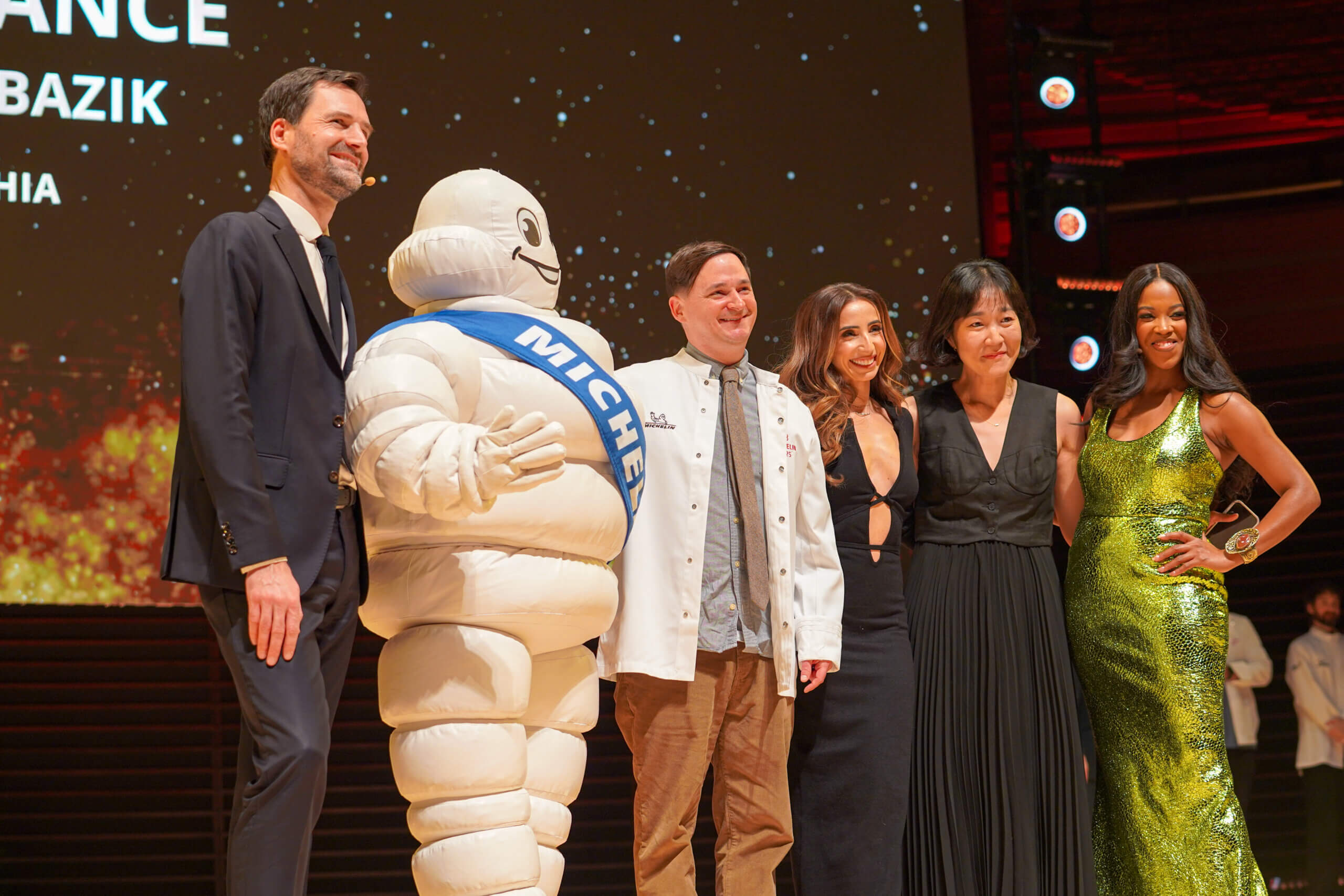 The Michelin mascot poses with a newly starred Michelin chef for a group photo with other dignitaries.