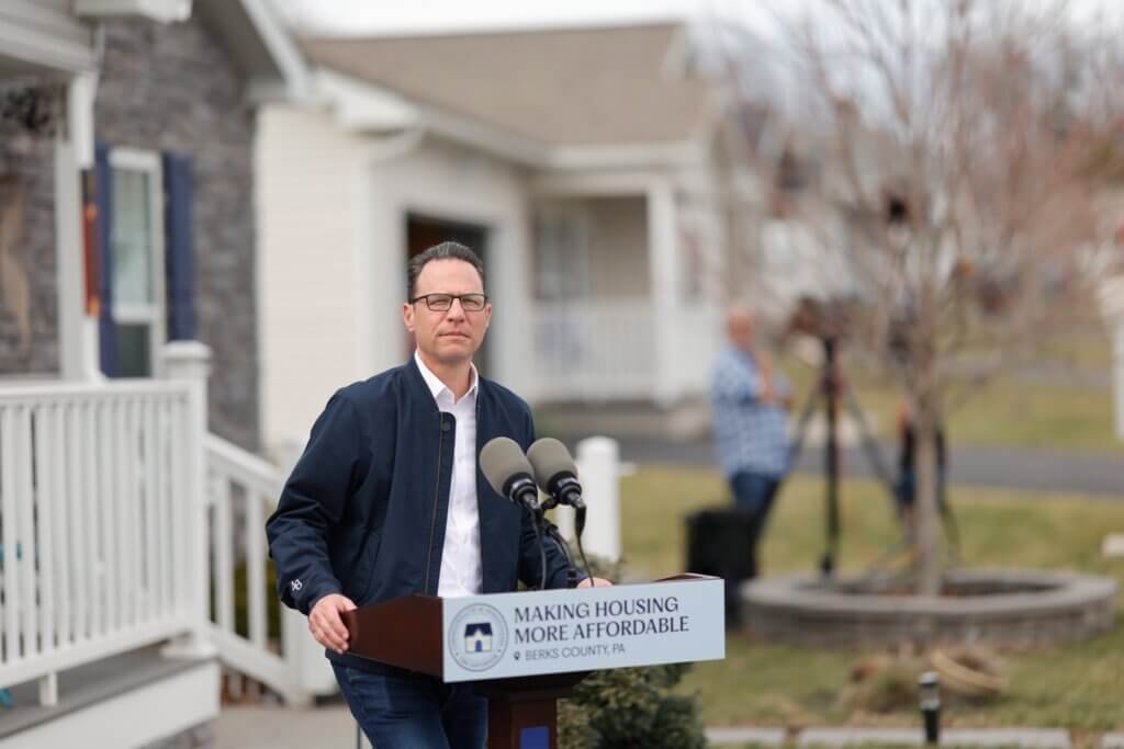Pennsylvania Governor Josh Shapiro speaking from an outdoor podium at a manufactured housing community in Berks County