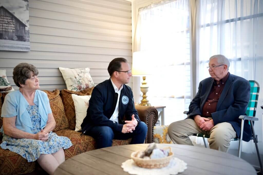 Pennsylvania Governor Josh Shapiro seated, speaking with a family at a manufactured housing community in Berks County