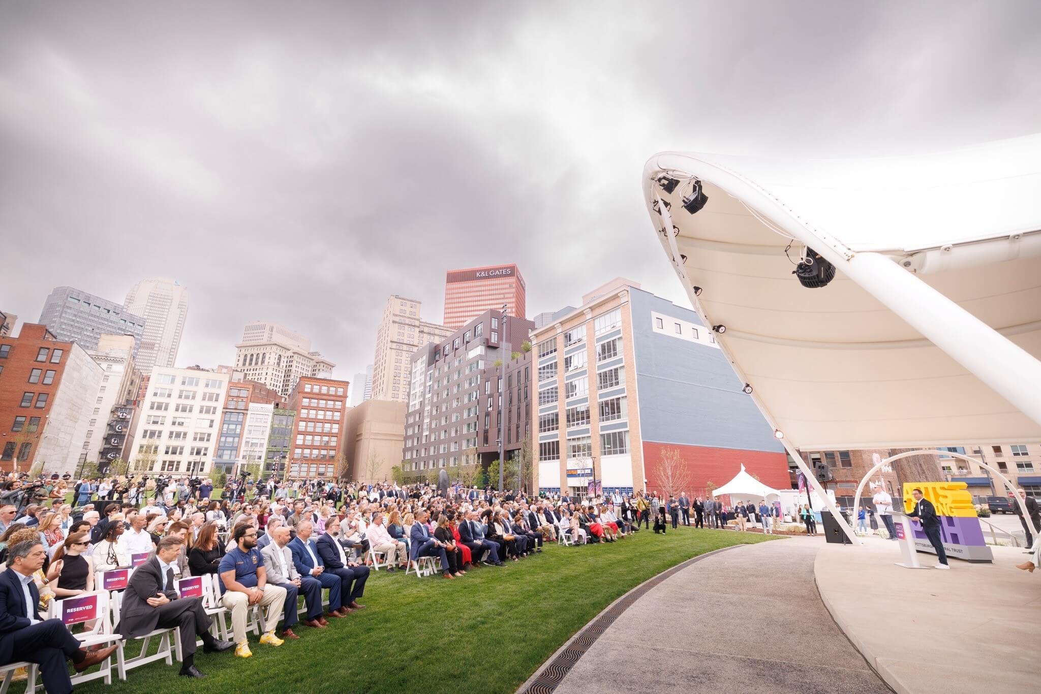 Pennsylvania Governor Josh Shapiro speaking from an outdoor podium on Opening of Arts Landing in Downtown Pittsburgh