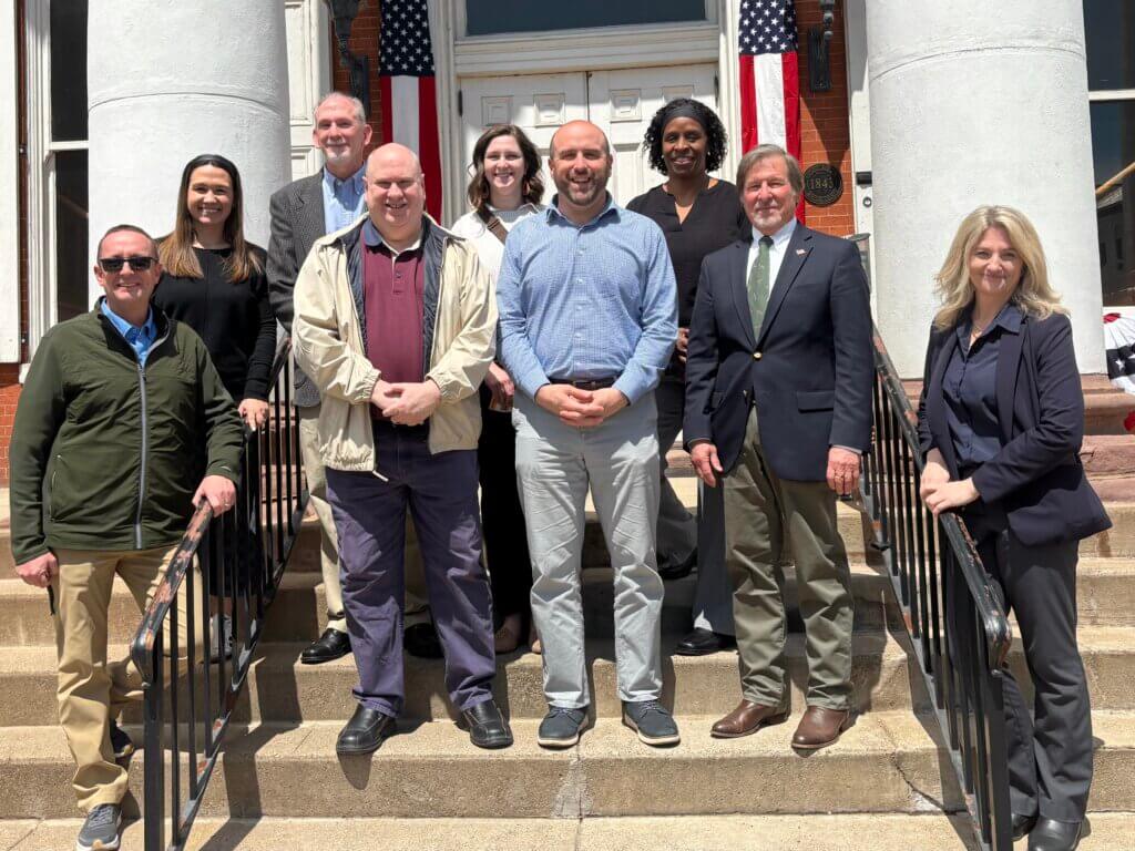Secretary Siger with owners and employees of several downtown Lewistown businesses posing on a set of stairs.