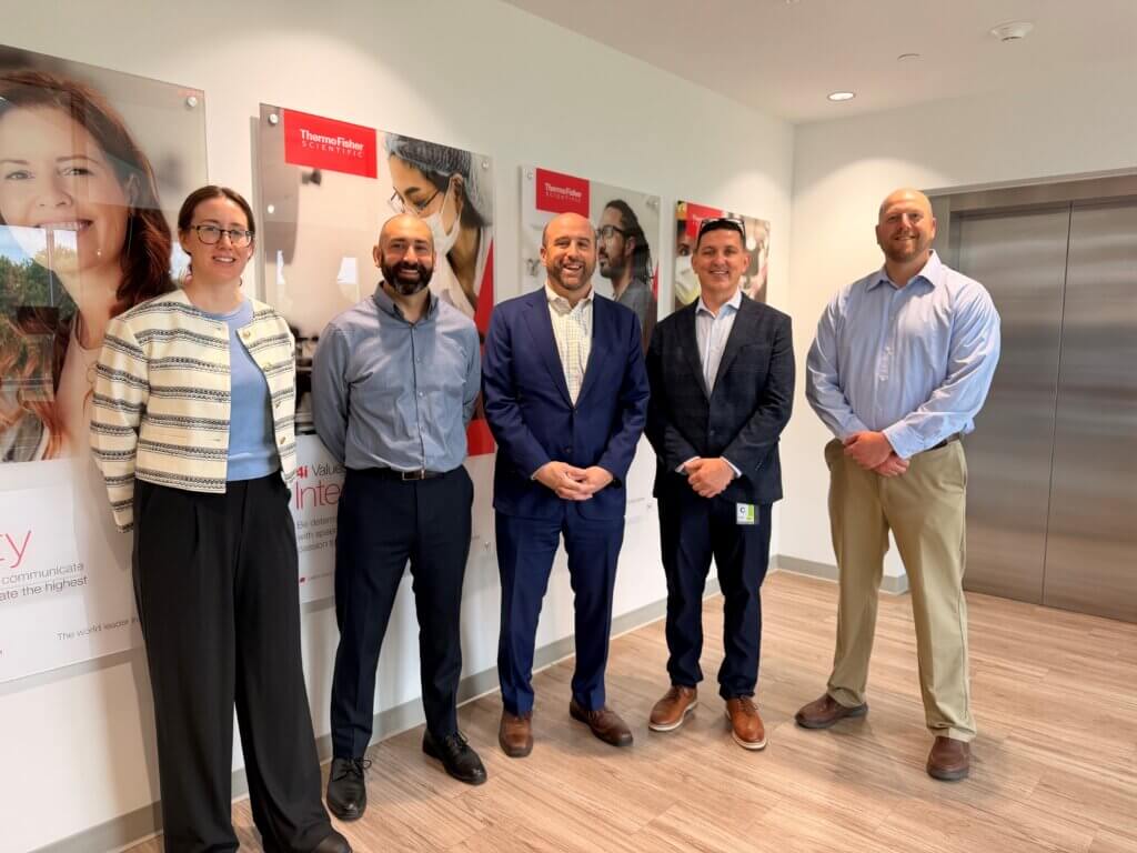 Rick Siger posing with crew of life science manufacturer Thermo Fisher Scientific Inc