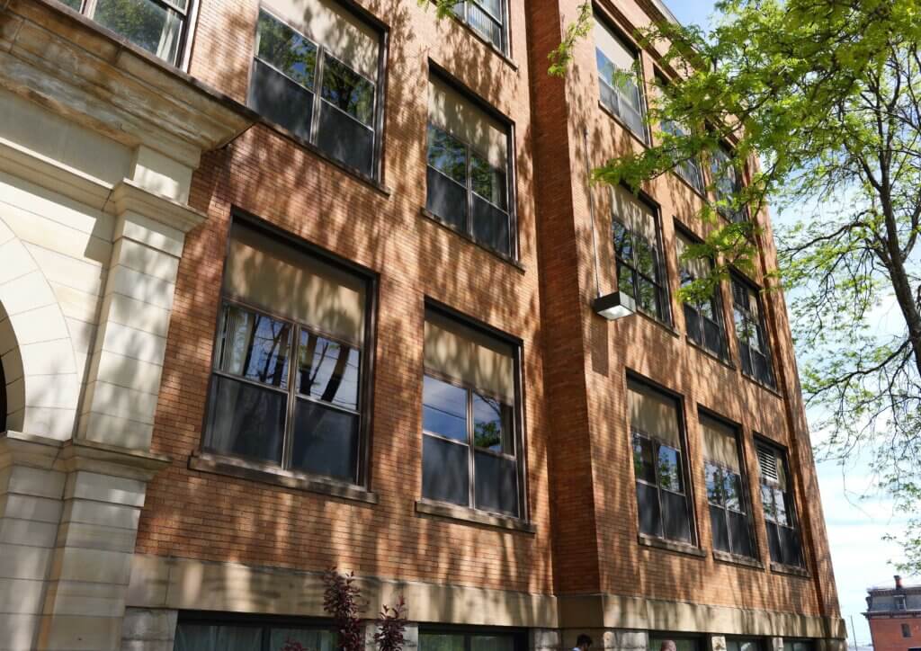Exterior shot of a brick wall with several windows at the Washington Square Schoolhouse Apartments housing project in the City of Erie